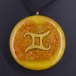 Round orange-yellow pendant necklace with gold Gemini symbol, close-up on black cord