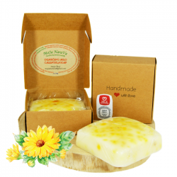 Ognjičevo milo s kartonasto embalažo, produktna fotografija z rumenimi cvetovi ognjiča