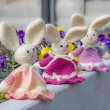 Three crocheted Easter bunnies in peach, pink and lilac dresses arranged on a stone ledge