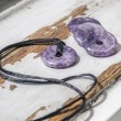 Dva lepidolit donut obeska s črnima vrvicama na leseni podlagi