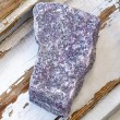 Block-shaped rough lepidolite stone piece in purple tones on rustic wood