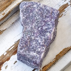 Block-shaped rough lepidolite stone piece in purple tones on rustic wood
