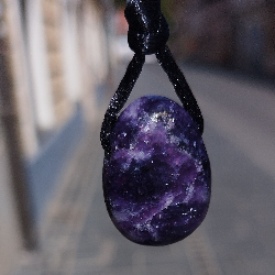 Bližnji posnetek obeska iz lepidolita z vijoličnim vzorcem na črni vrvici