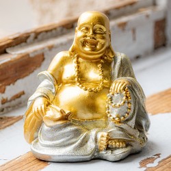 Gold-silver smiling Buddha figurine, close view on rustic wooden surface