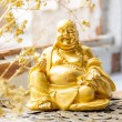 Golden yellow laughing Buddha statue on Chinese coins, feng shui decor