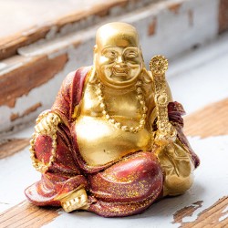 Gold-red smiling Buddha figurine on rustic wooden surface, front view