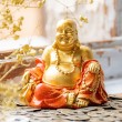 Gold-orange laughing Buddha statue on Chinese coins, feng shui decor