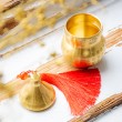 Close-up of brass Wu Lou gourd container and lid with red tassel on white wooden background